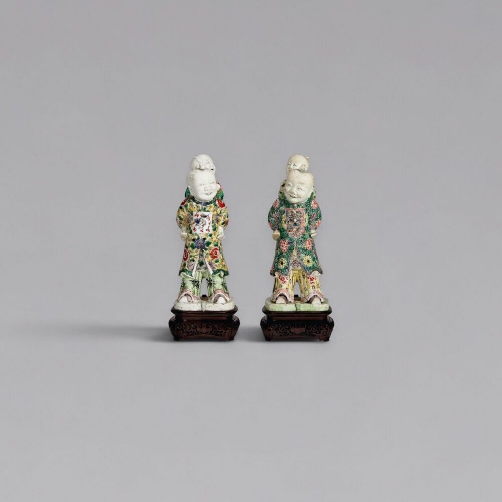 A pair of famille-verte biscuit-glazed piggyback boys