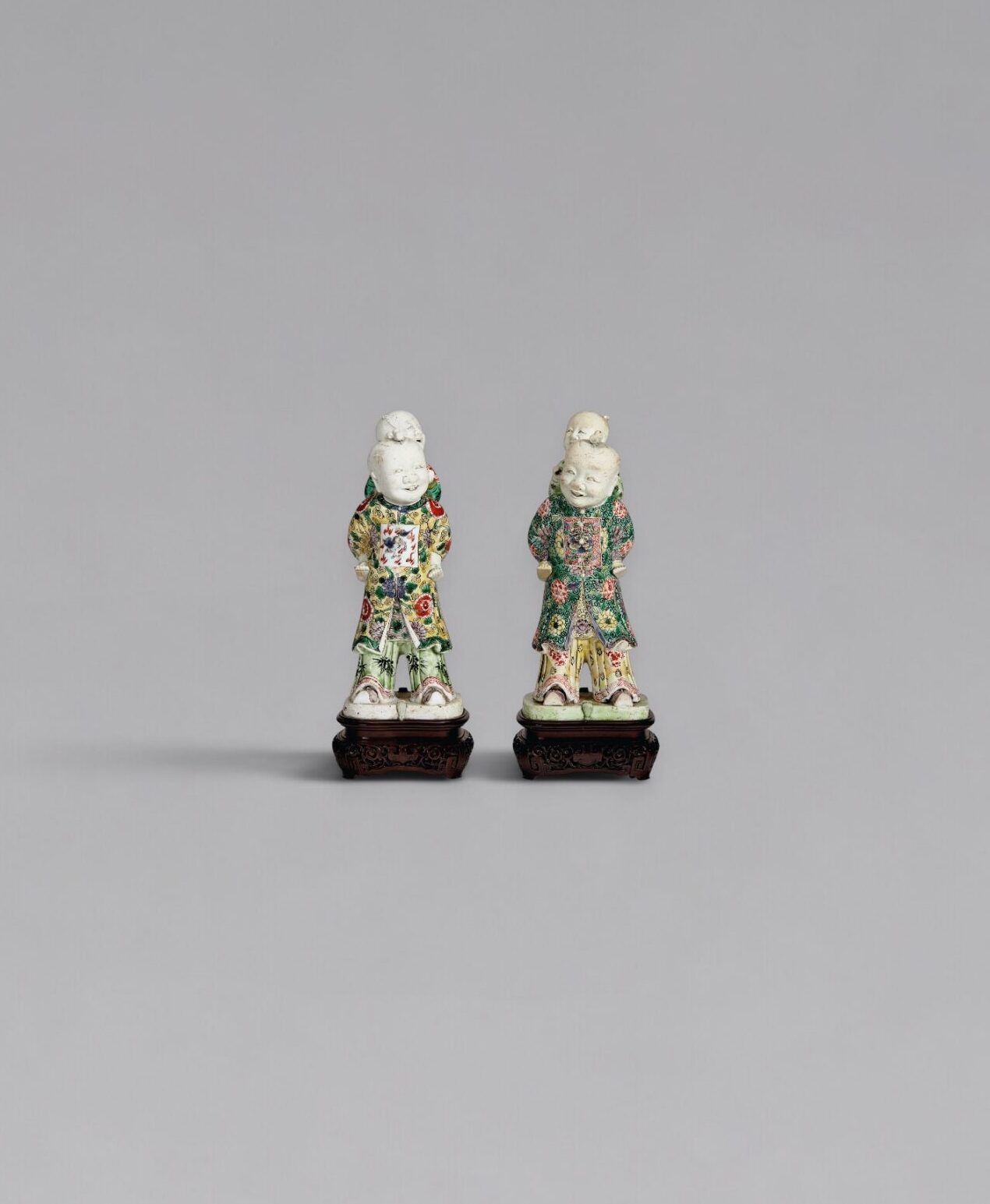 A pair of famille-verte biscuit-glazed piggyback boys